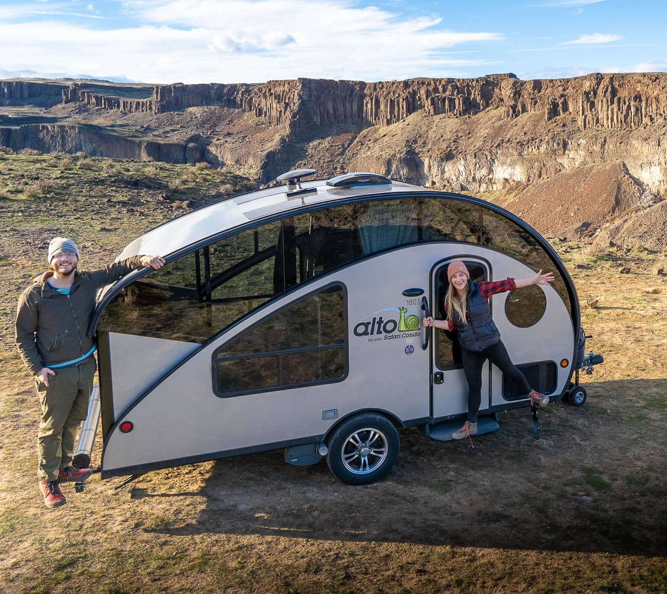 Couple standing by their Safari Condo Alto R1723 trailer in Frenchman Coulee in Washington