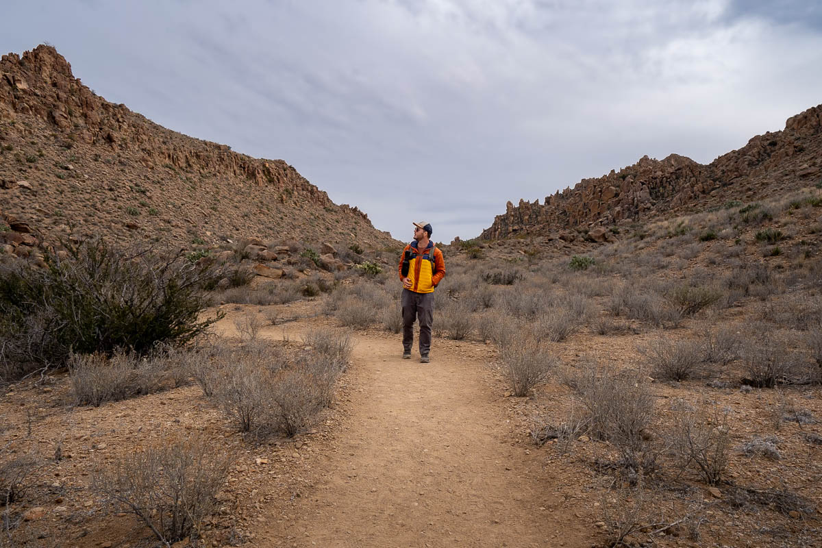 Man hiking along the Balanced Rock Trail with rock formations in the background in Big Bend National Park in Texas