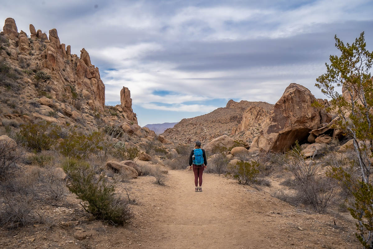 Woman walking along the Balanced Rock Trail with rock formations surrounding the trail in Big Bend National Park in Texas