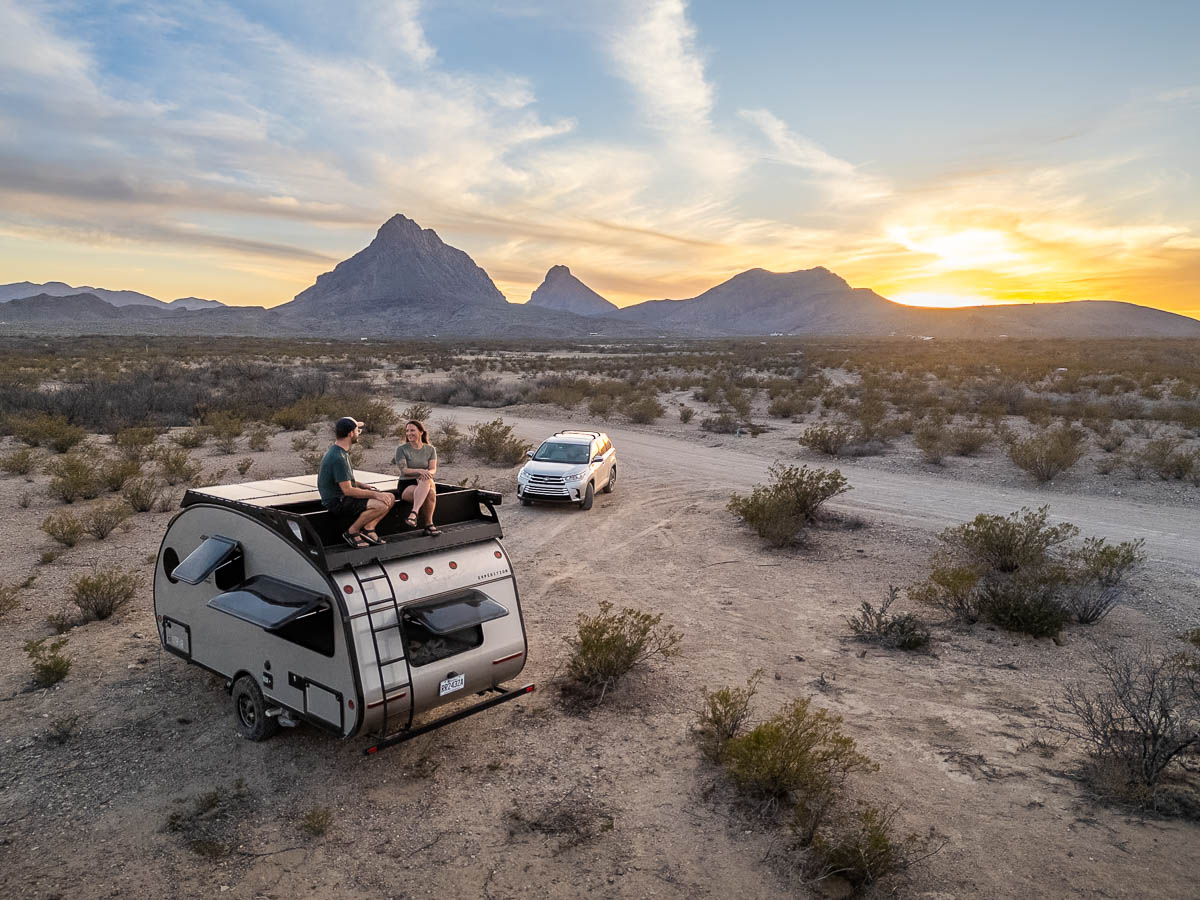 Couple sitting on top of their Safari Condo Alto Expedition trailer in Terlingua, Texas at sunset