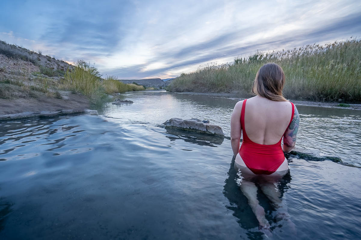 Woman sitting in Langford Hot Springs and looking at the Rio Grande in Big Bend National Park