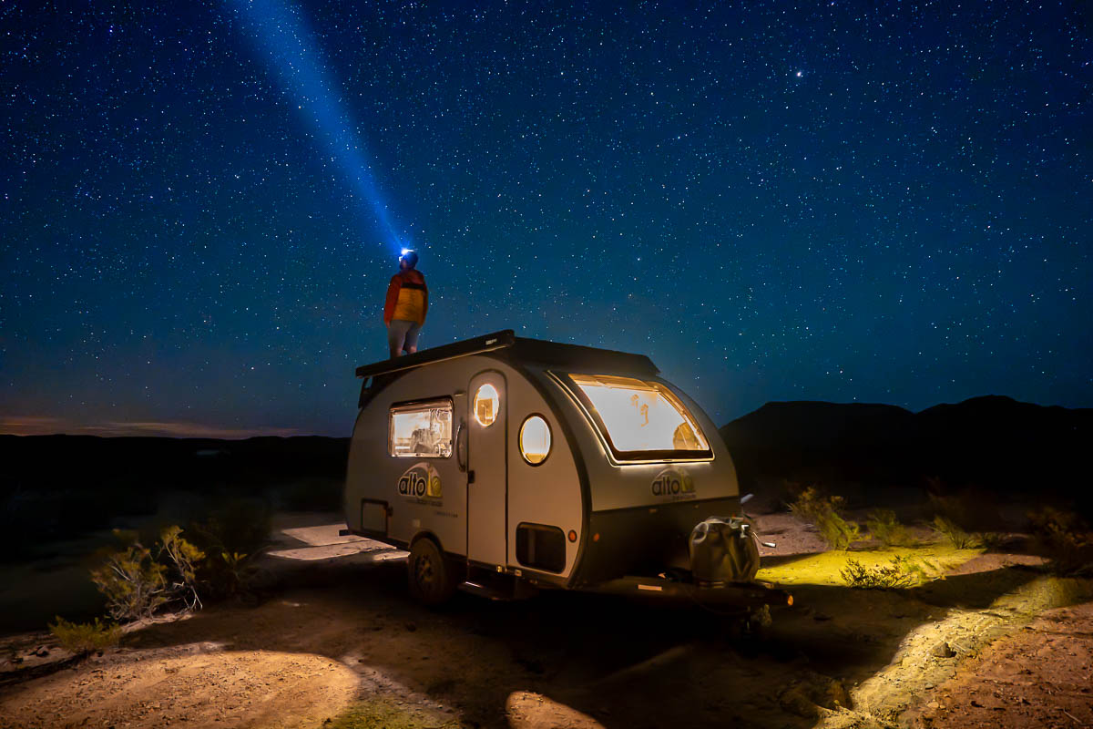 Man standing on top of his Safari Condo Alto Expedition F1743 in the desert of Terlingua, Texas at night with the night sky above him