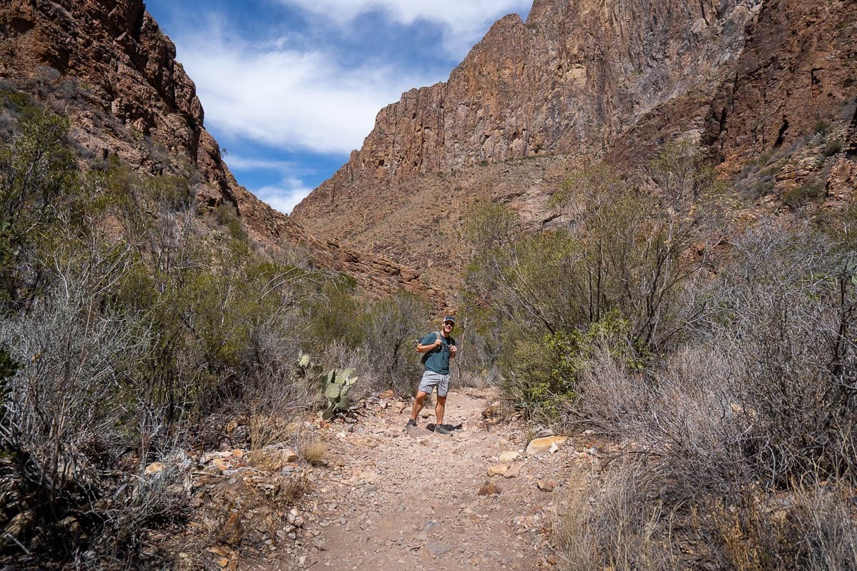 Man hiking down the Window Trail with canyon walls in the background in Big Bend National Park