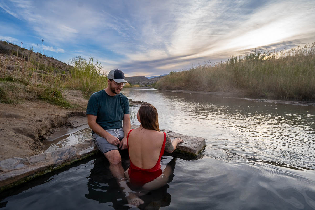 Couple sitting in the Big Bend Hot Springs next to the Rio Grande River in Big Bend National Park in Texas