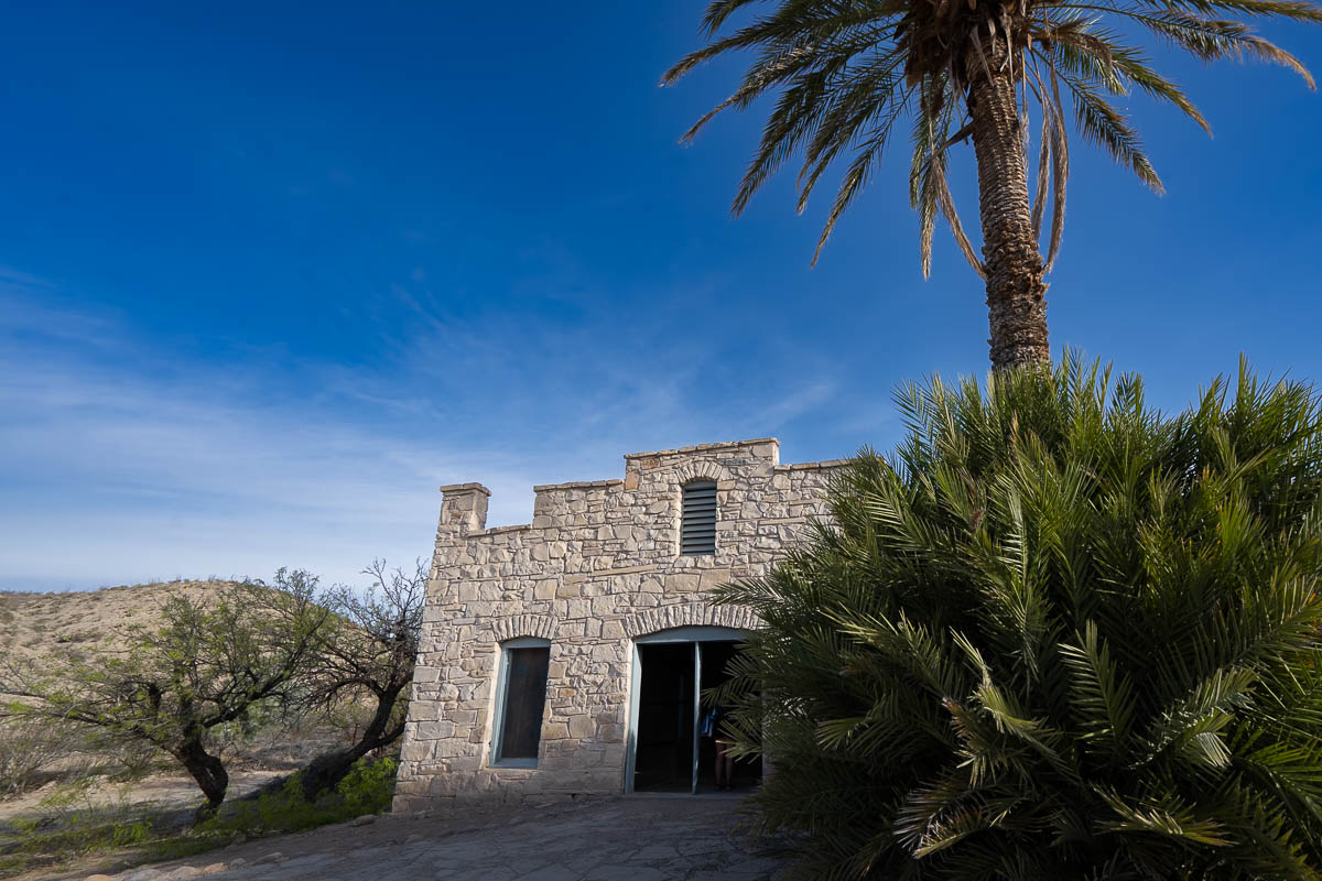 Historic building for the Langford Hot Springs Resort with a palm tree  next to it along the Big Bend Hot Springs trail in Big Bend National Park in Texas