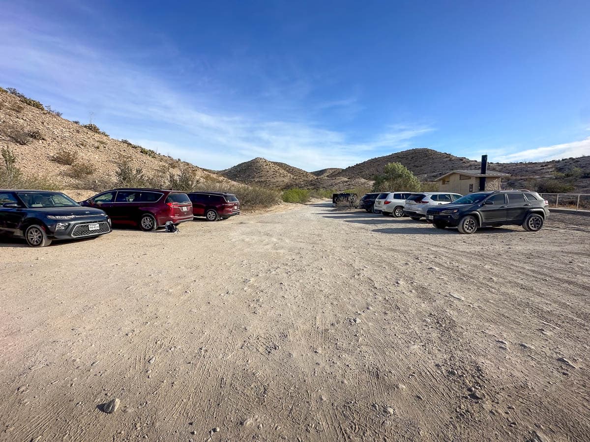 Dirt parking lot with cars parked  at the Big Bend Hot Springs trailhead in Big Bend National Park in Texs