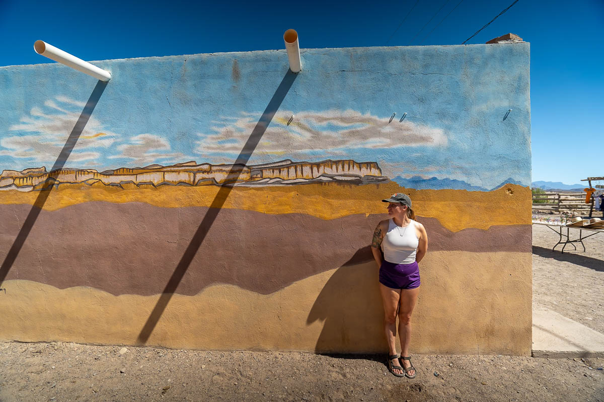 Woman standing in front of a mural painted on the front of a building in Boquillas del Carmen, Mexico