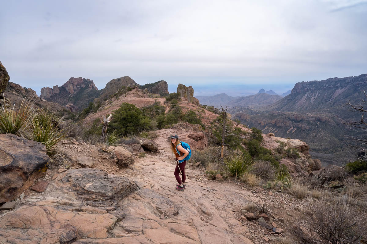 Woman walking along a ridgeline with the Chisos Mountains in the background along the Lost Mine Trail in Big Bend National Park in Texas