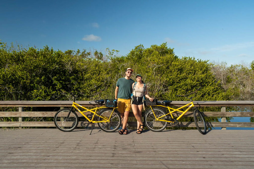 Couple standing along a wooden boardwalk next to bikes along the Shark Valley bike trail in Everglades National Park