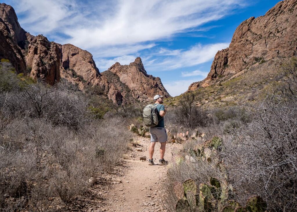 Man standing along the Window Trail with the Chisos Mountains in the backgroung in Big Bend National Park