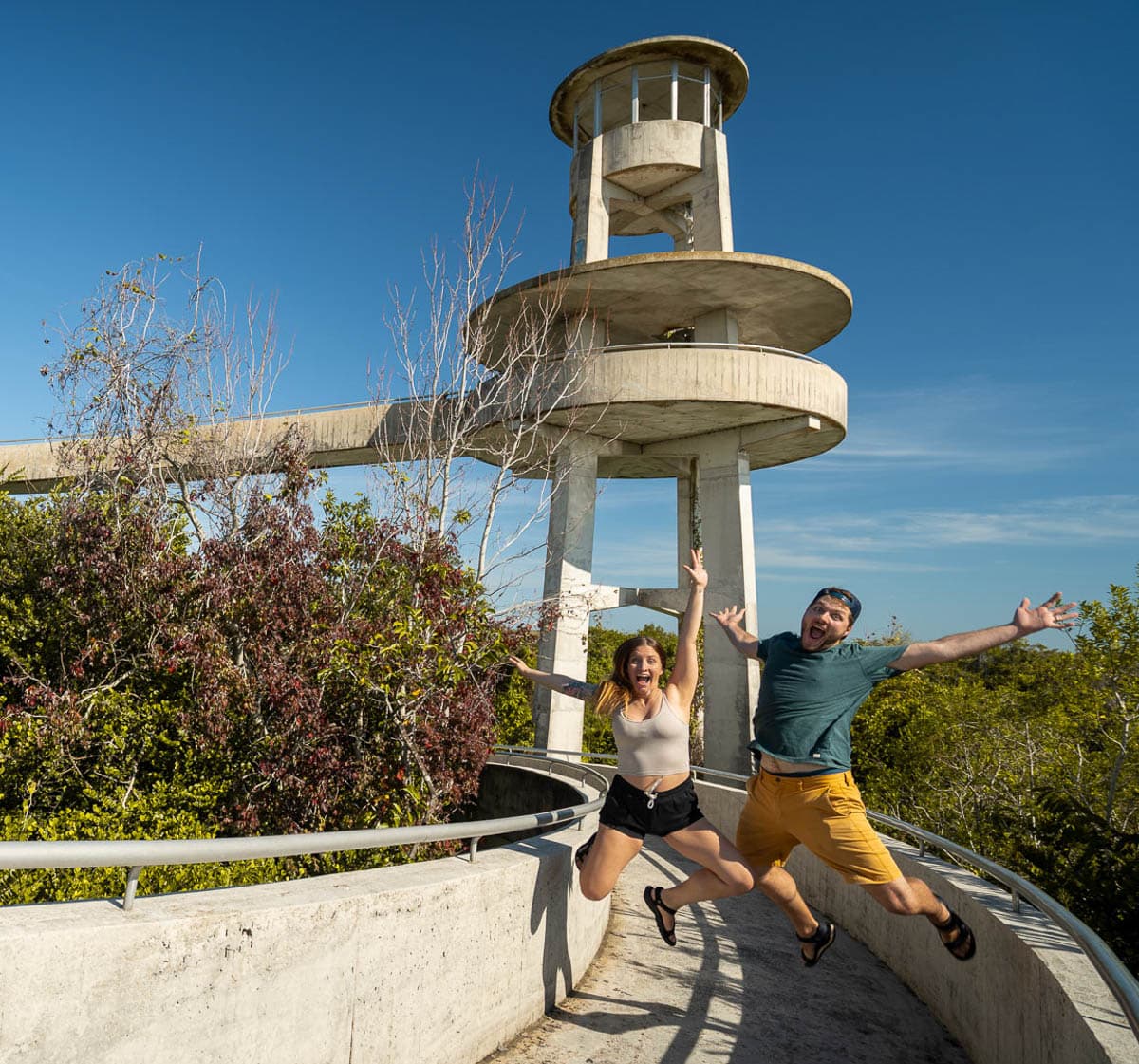 Couple jumping in front of the Shark Valley Observation Tower along the Shark Valley trail in Everglades National Park