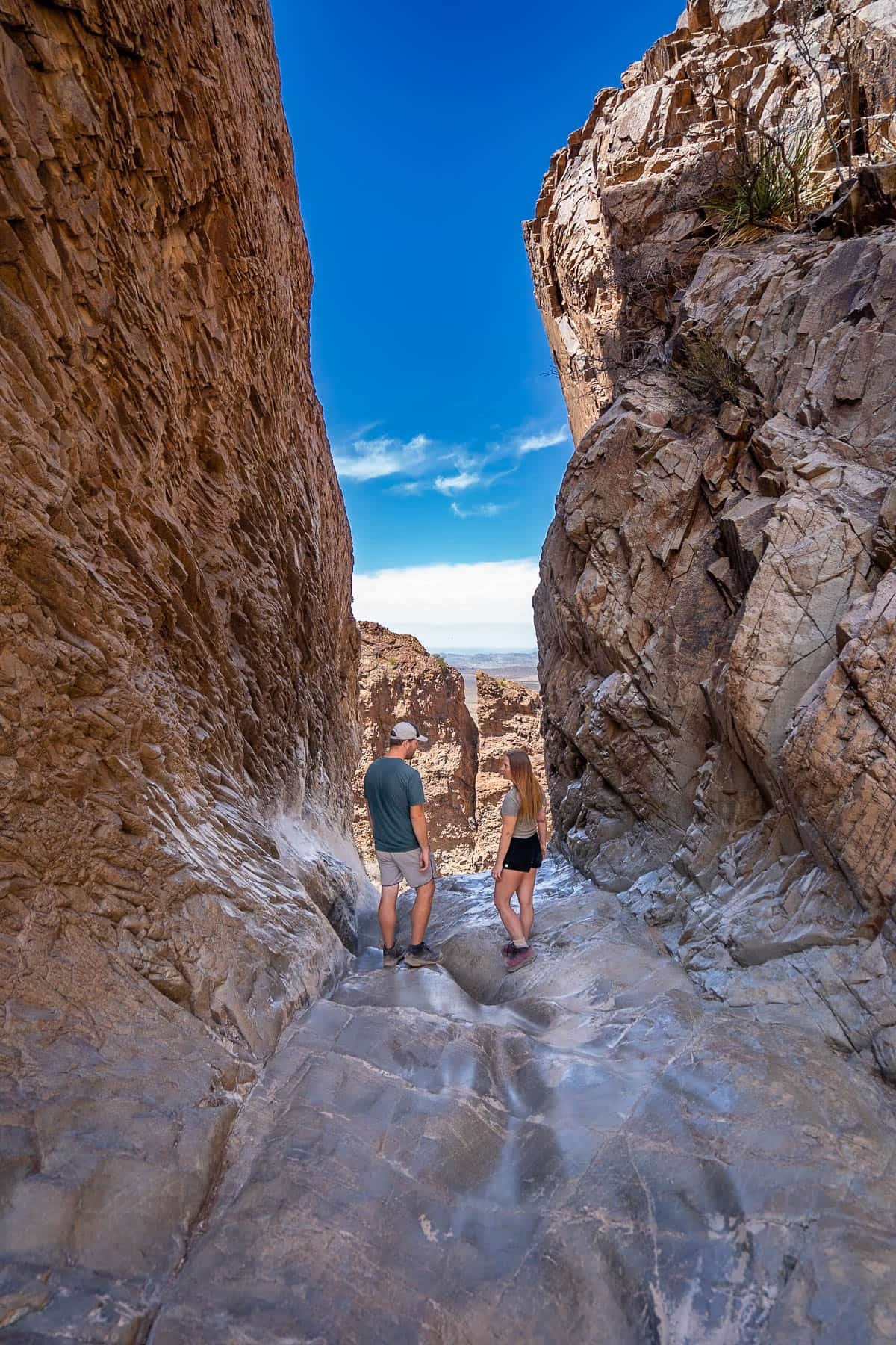 Couple standing in the window with the Chisos Mountains in the background along the Window Trail in Big Bend National Park in Texas