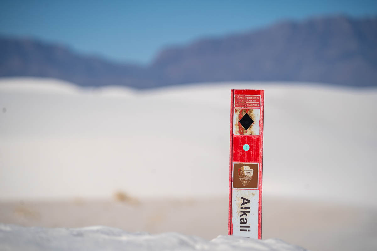 Marker for the Alkali Flat Trail in a white sand dune in White Sands National Park in New Mexico