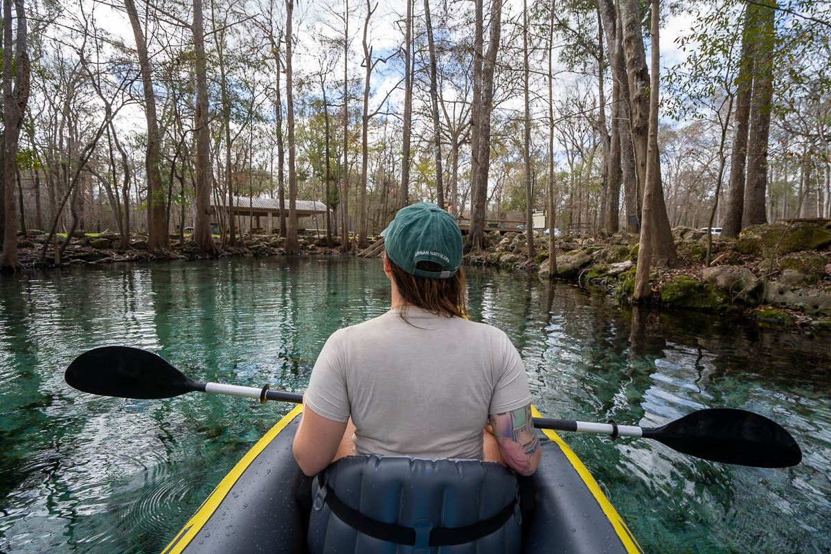 Woman kayaking in Ginnie Springs with cypress and oak trees on either side in High Springs, Florida