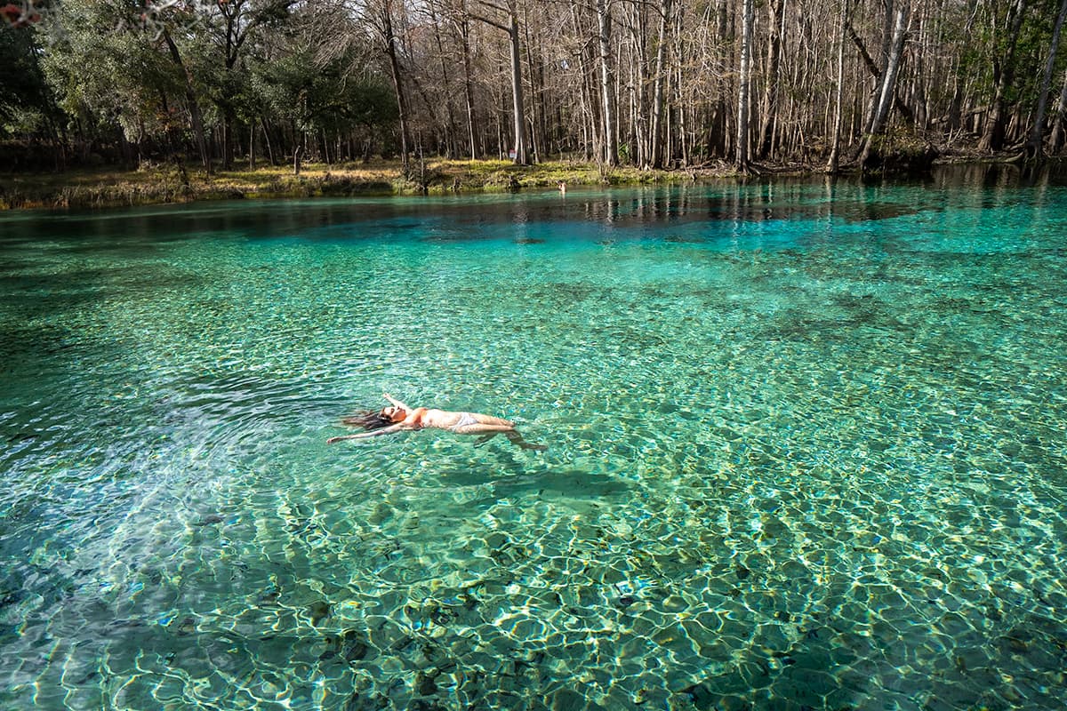 Woman floating in turquoise water in Ruth B. Gilchrist Blue Springs State Park in High Springs, Florida