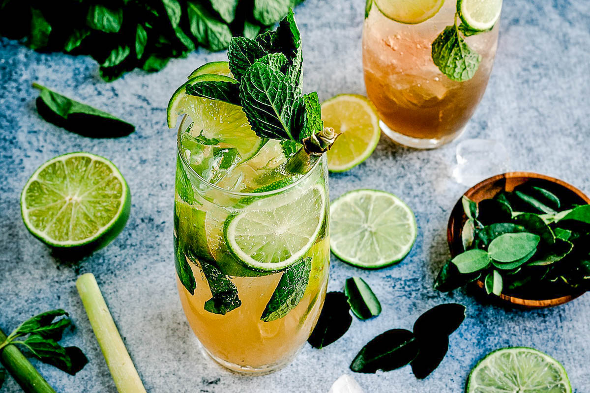 Mojito on a countertop, surrounded by lime and mint