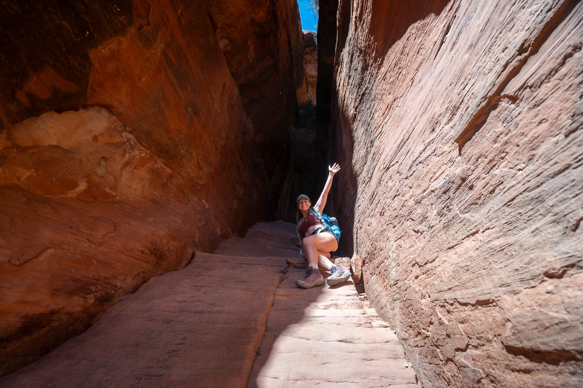 Woman climbing up a slickrock incline into the Subway Cave in Sedona, Arizona