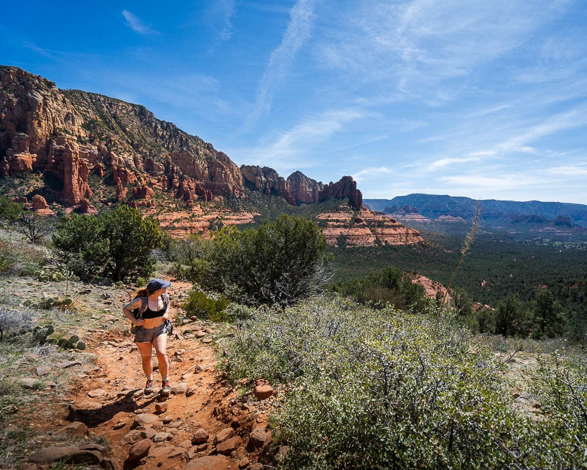 Woman hiking along the Jordan Road trail with red rock formations in the background in Sedona, Arizona