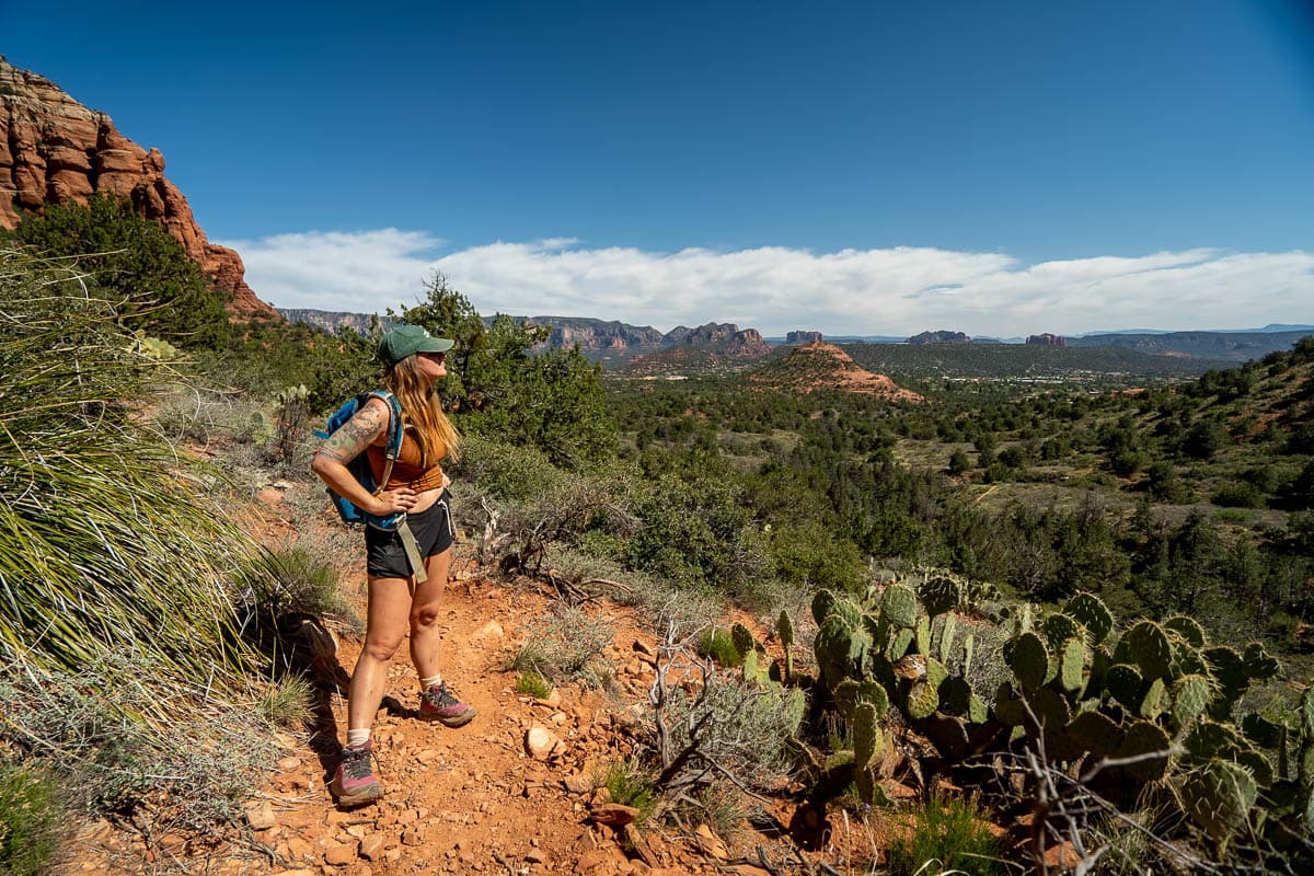 Woman standing along the Keyhole Cave Trail with rock formations in the background in Sedona, Arizona