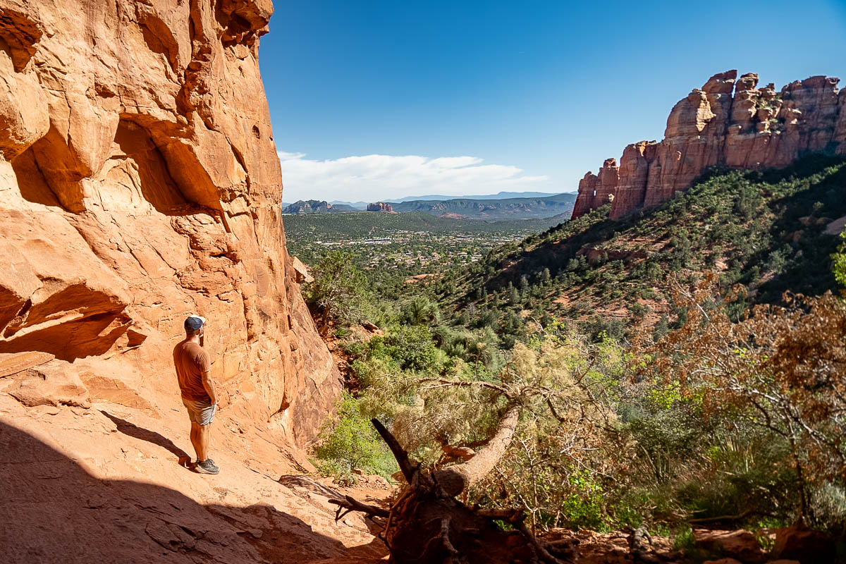 Man standing at the opening of the Keyhole Cave, looking at the nearby rock formation in Sedona, Arizona