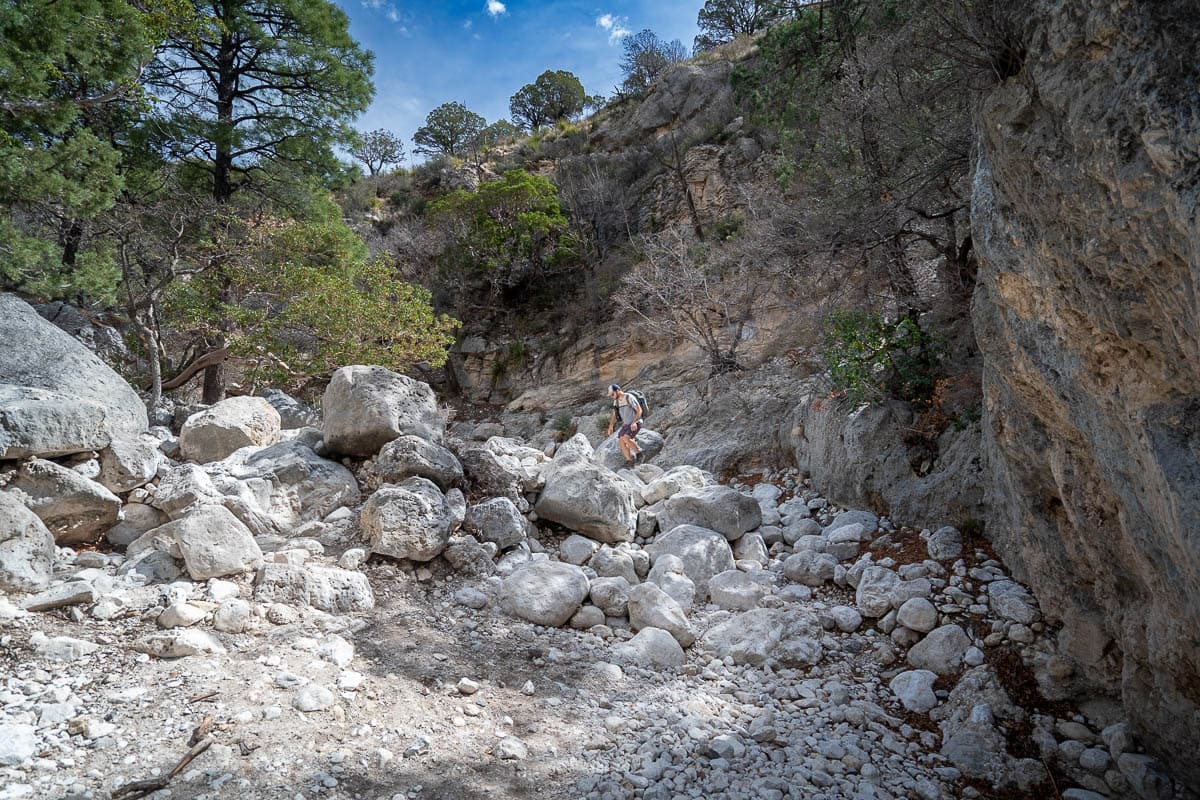 Man climbing on boulders along a wash on the Devil's Hall Trail in Guadalupe Mountains National Park in Texas