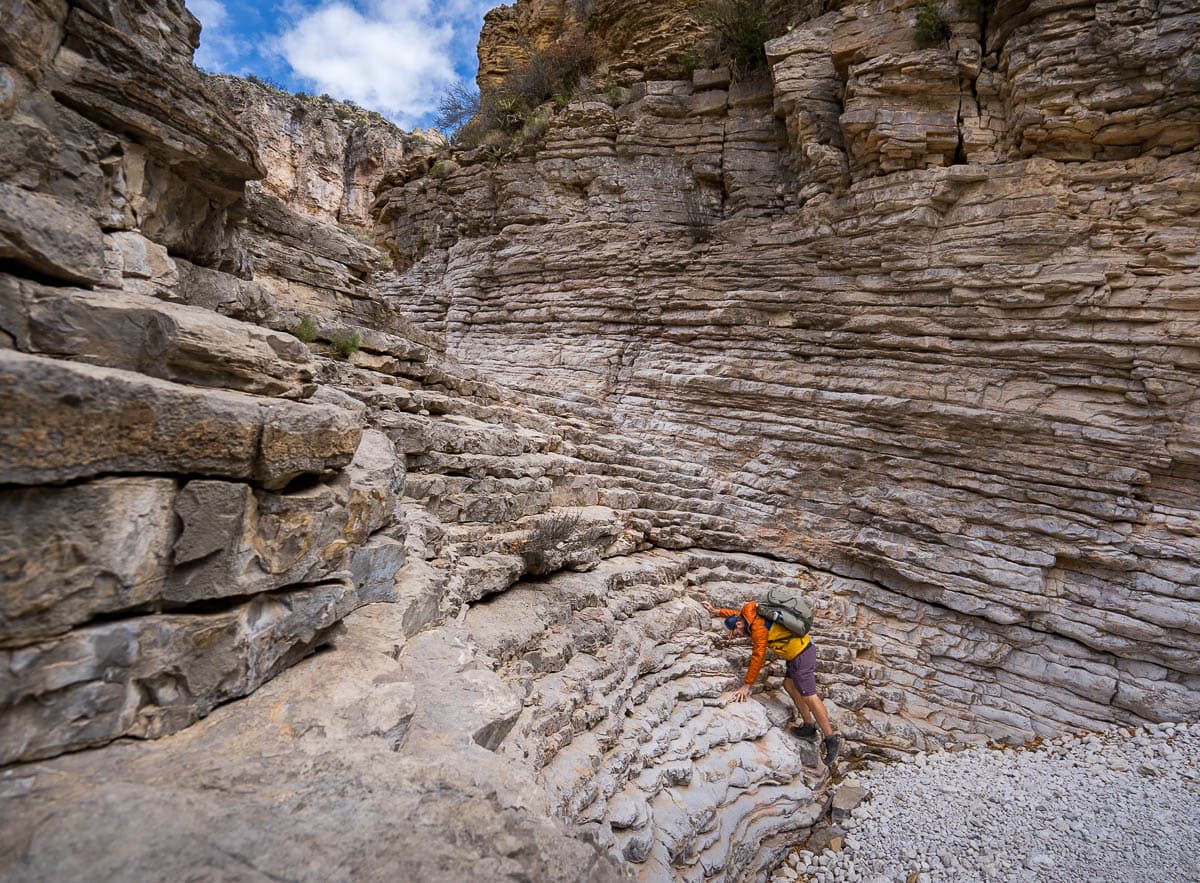 Man climbing up rock layers along the Devil's Hall Trail in Guadalupe Mountains National Park in Texas