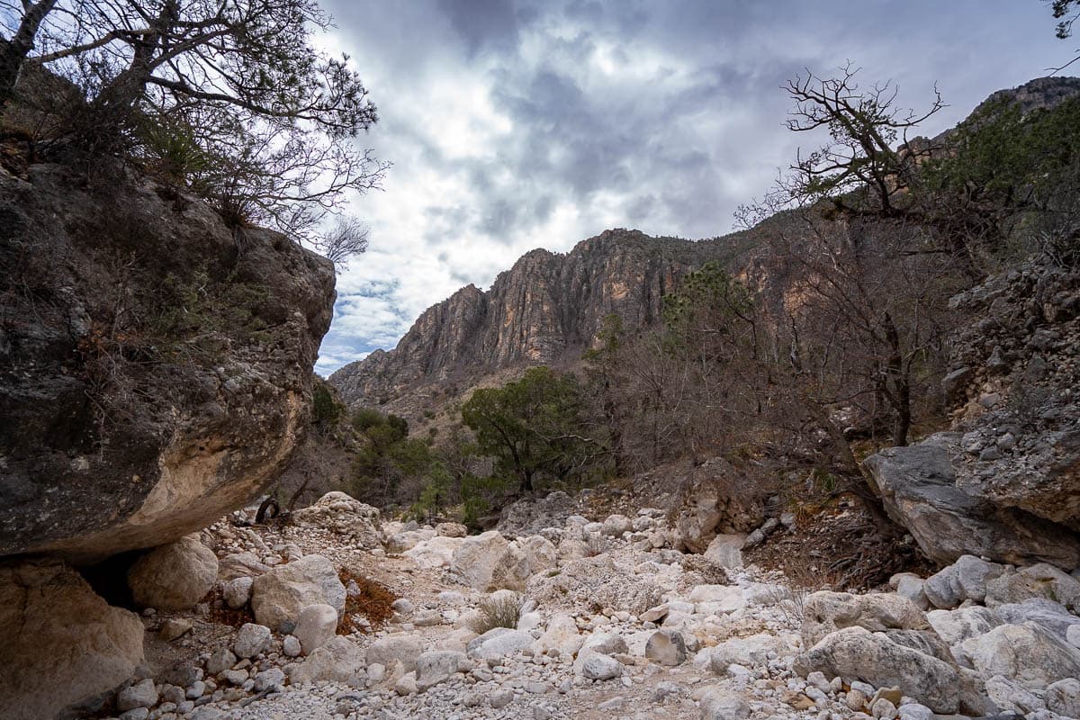 Rocky boulders along a wash with mountains in the background along the Devil's Hall Trail in Guadalupe Mountains National Park in Texas