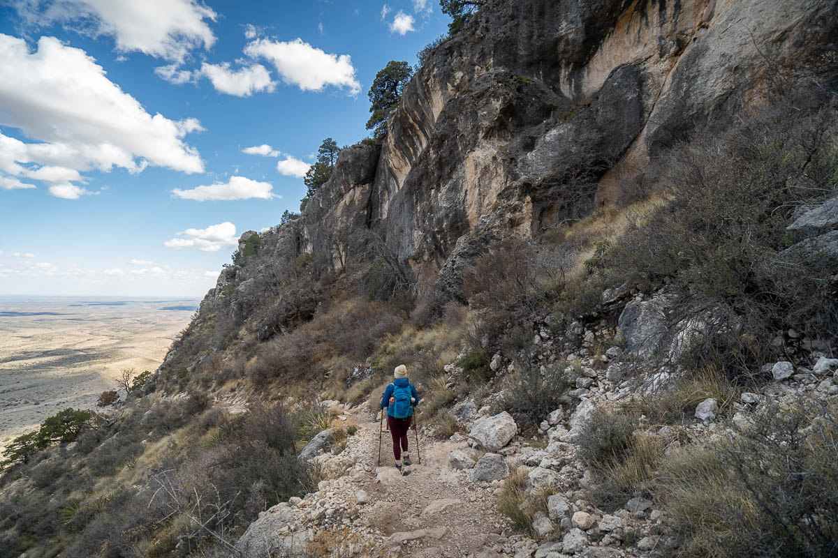 Woman hiking along a switchback on the Guadalupe Peak Trail with the Chihuahuan Desert in the background in Guadalupe Mountains National Park in Texas