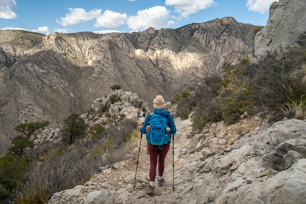 Woman walking along a ridgeline of the Guadalupe Peak Trail with Hunter Peak in the background in Guadalupe Mountains National Park in Texas