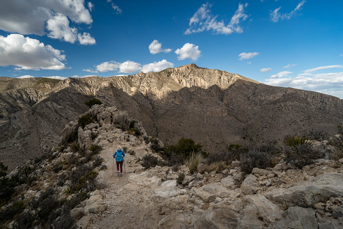 Woman hiking along a ridge line on the Guadalupe Peak Trail with Hunter Peak in the background in Guadalupe Mountains National Park in Texas