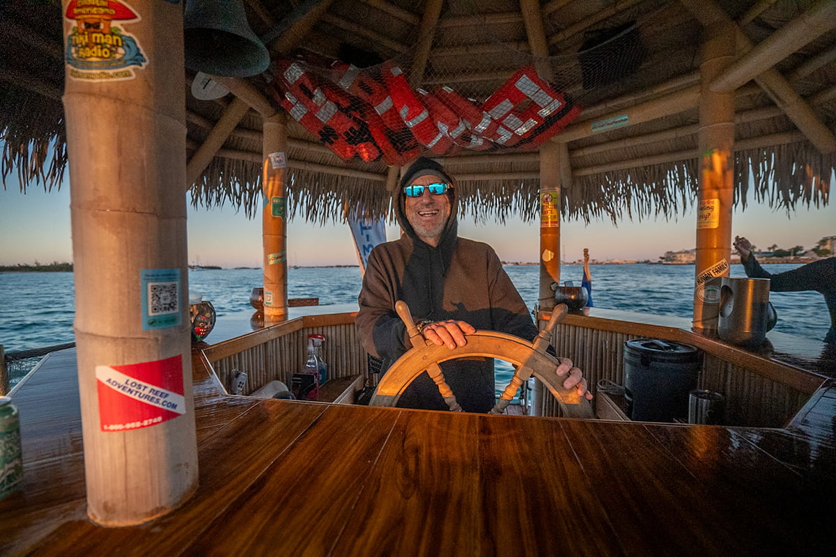 Captain at the helm of a tiki boat at sunset in Key West Harbor in Key West in the Florida Keys