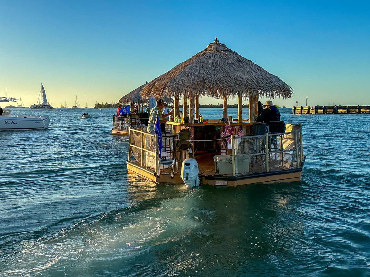 People sitting around a bar on a tiki boar at sunset near Mallory Square in Key West, Florida