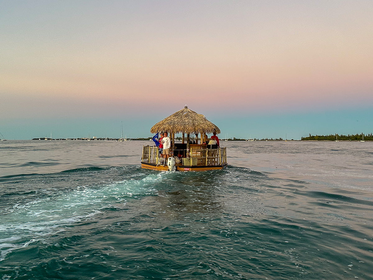 People standing on a tiki boat at sunset cruising along the Key West Harbor in Key West, Florida