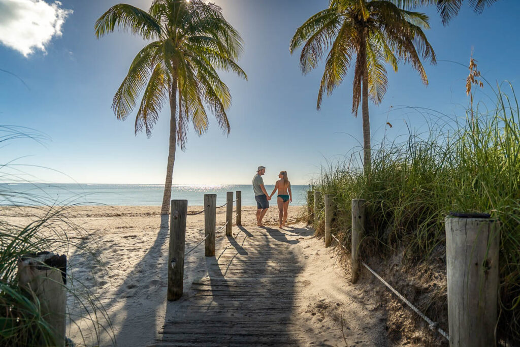 Couple holding hands on wooden boardwalk on Smathers Beach in Key West, Florida