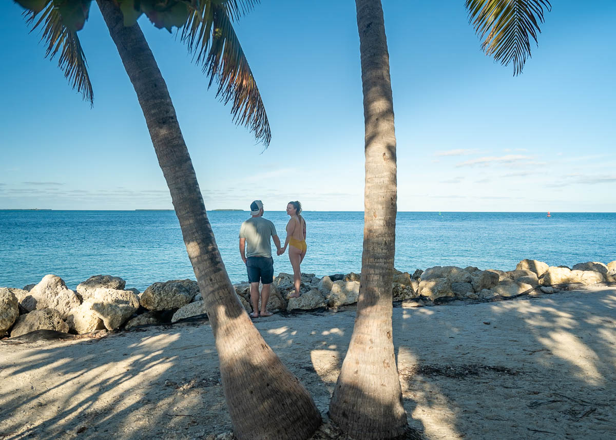 Couple holding hands near palm trees  at the beach in Fort Zachary Taylor Historic Site in Key West in Florida Keys, Florida