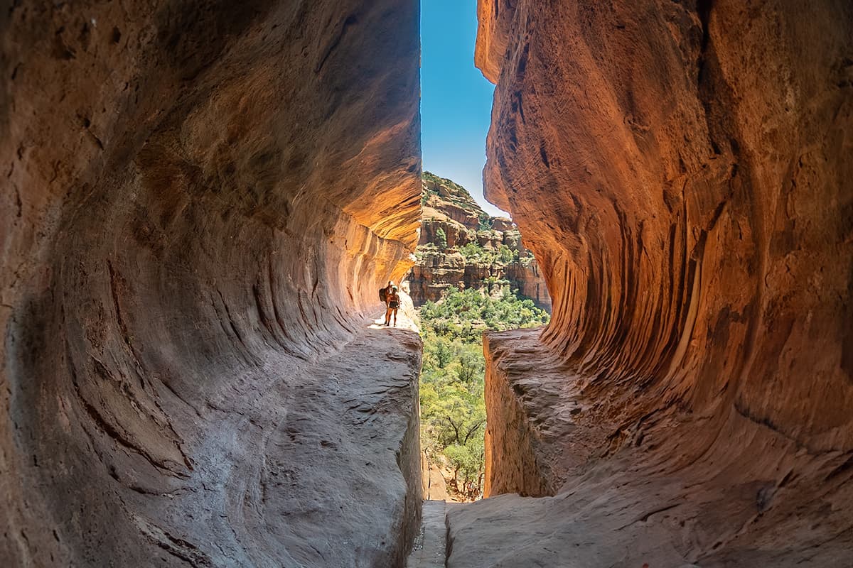 Couple standing on a ledge along the Subway Cave with rock formations in the background in Sedona, Arizona