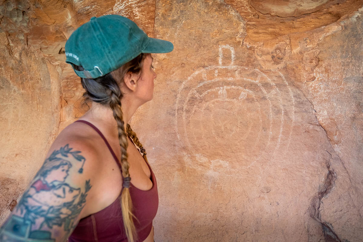 Woman looking at a petroglyph on a wall near the Subway Cave in Sedona, Arizona