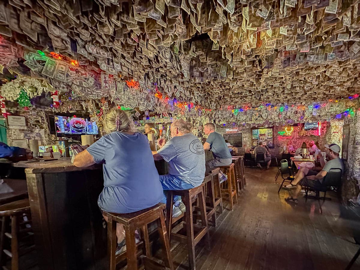 People sitting at a bar at No Name Pub, with dollar bills hanging from the ceiling, at Big Pine Key in the Florida Keys