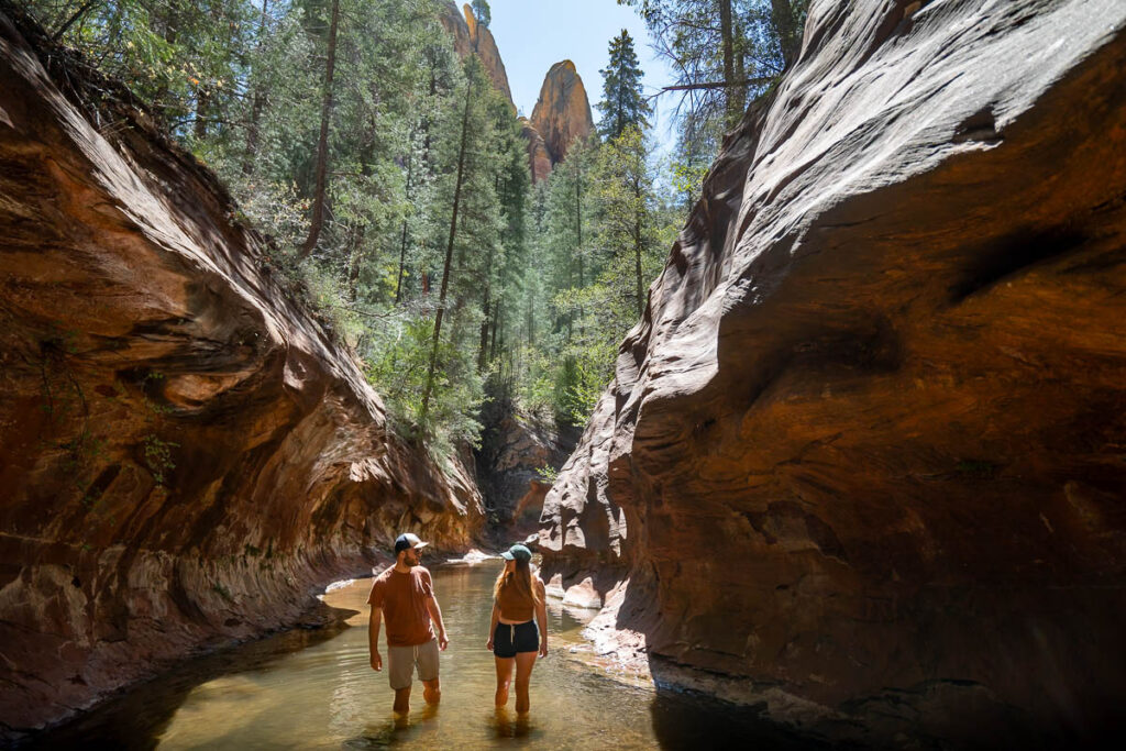 Couple hiking through slot canyon along the West Fork of Oak Creek in the West Fork Trail in Sedona, Arizona