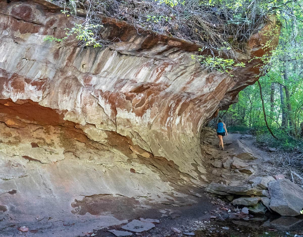 Woman hiking up a rocky pathway along a cliffside along the West Fork Trail in Sedona, Arizona