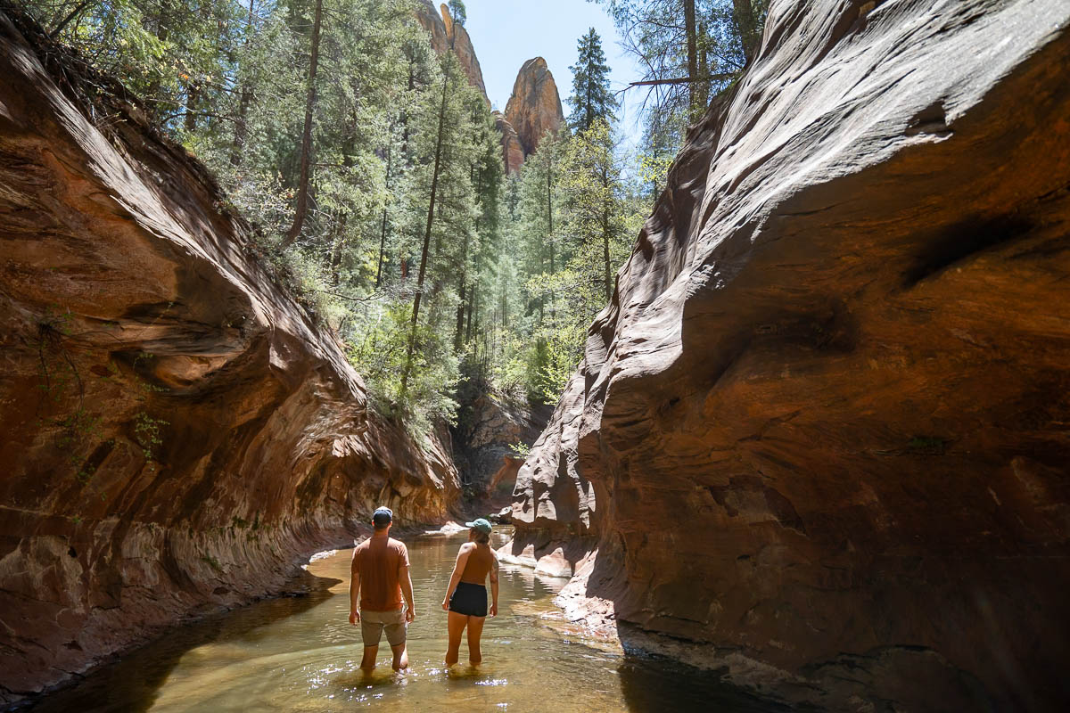 Couple hiking down the West Fork of Oak Creek in a slot canyon along the West Fork of Sedona, Arizona