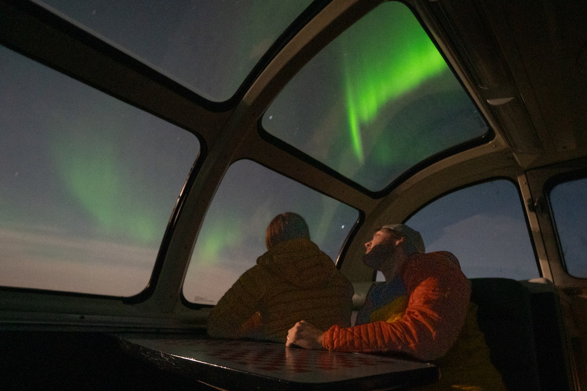 Couple looking at the Northern Lights in the Skyline dome car in Via Rail train to Churchill, Manitoba