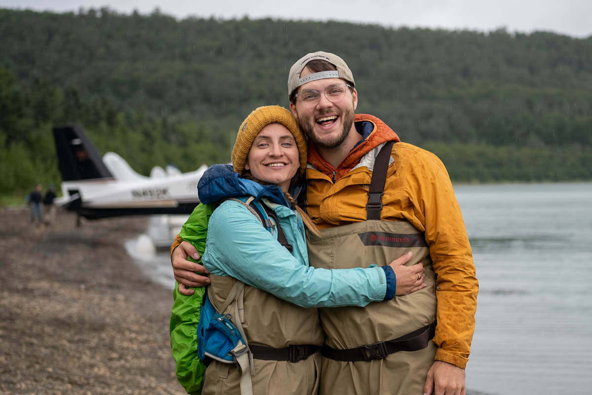 Couple smiling in front of a seaplane on Naknek Beach in Katmai National Park in Alaska