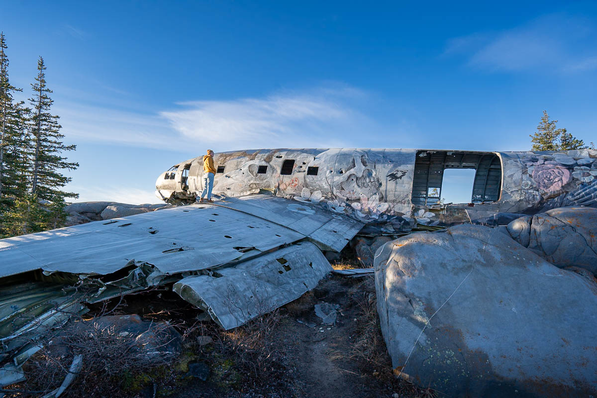 Woman standing on the wing of the Miss Piggy plane wreck in Churchill, Manitoba