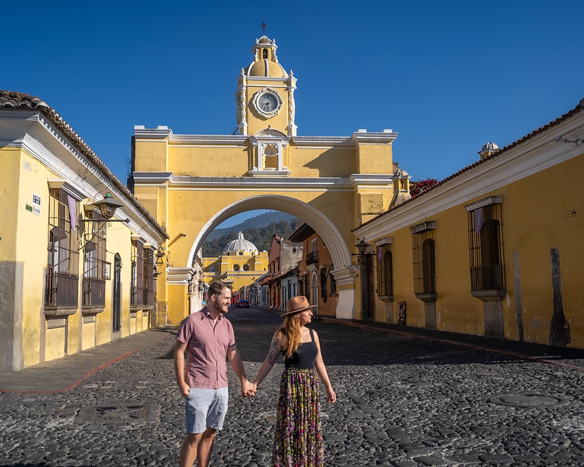 Couple holding hands in front of the Santa Catalina Arch in Antigua, Guatemala