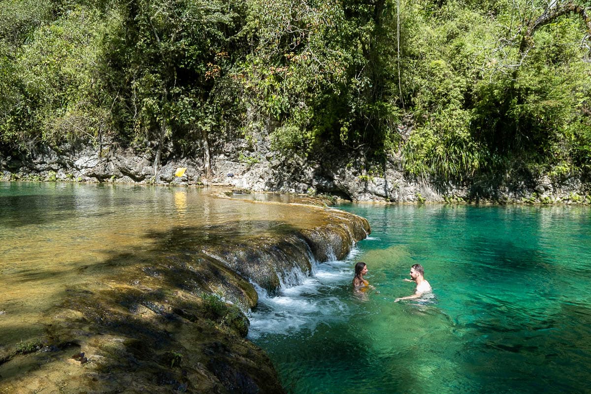 Couple swimming near a waterfall in Semuc Champey, Guatemala