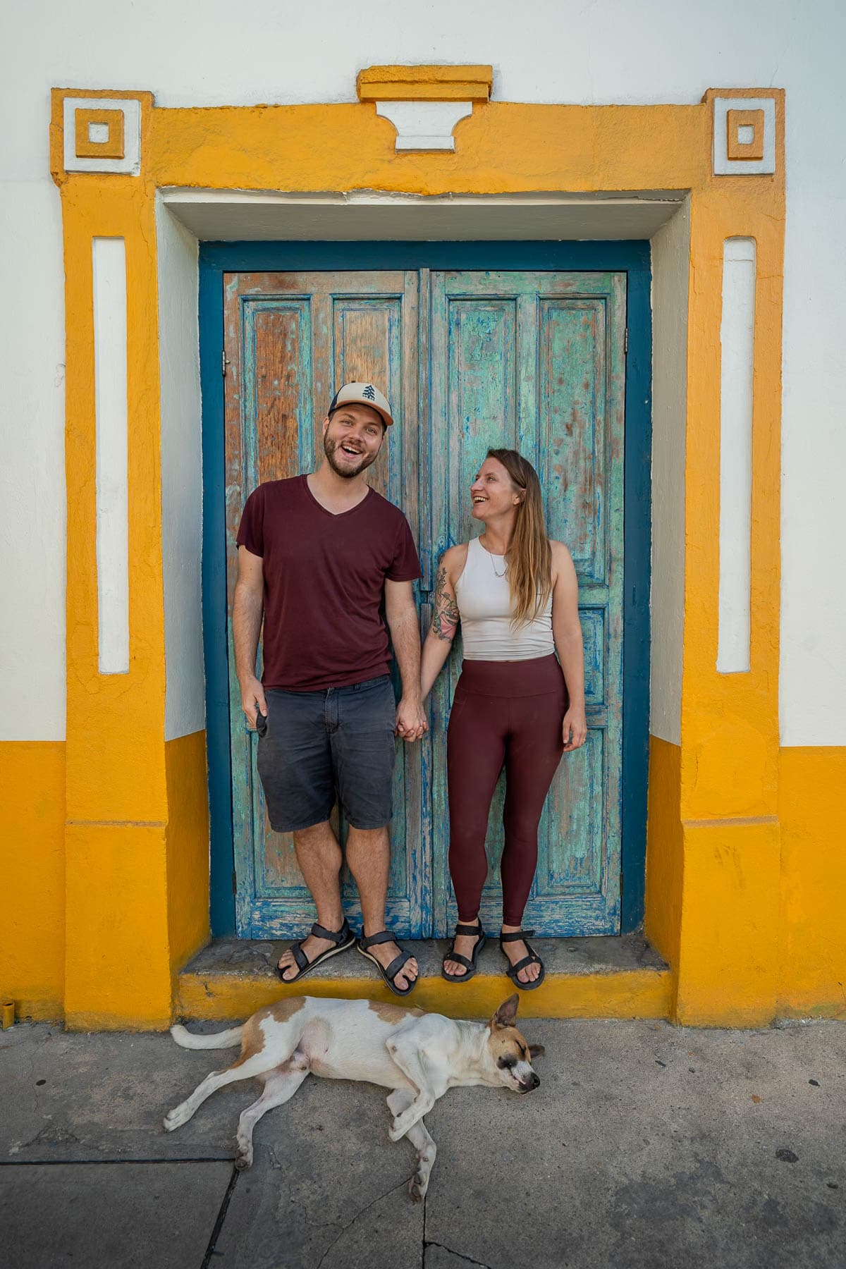 Couple holding hands in front of colorful doorway in Flores, Guatemala