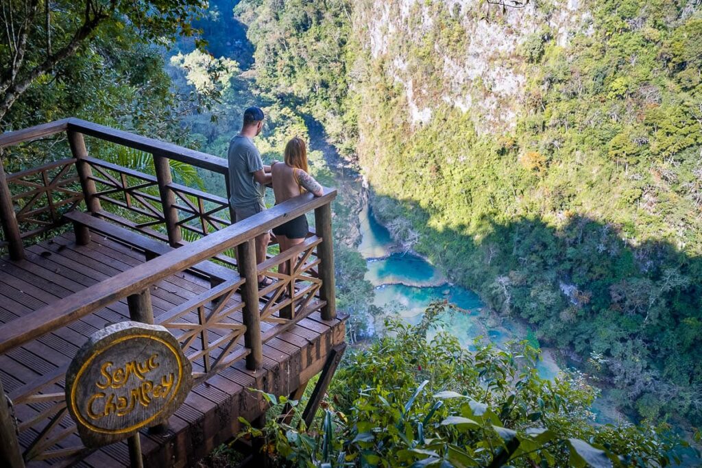 Couple standing on a wooden platform overlooking the pools in Semuc Champey in Guatemala