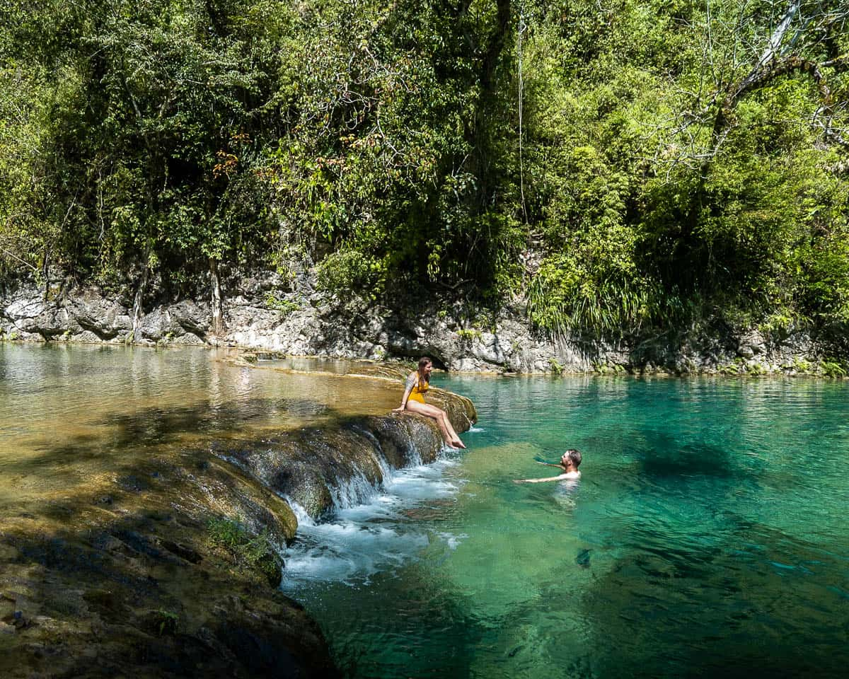 Couple sitting on a waterfall in Semuc Champey, Guatemala 