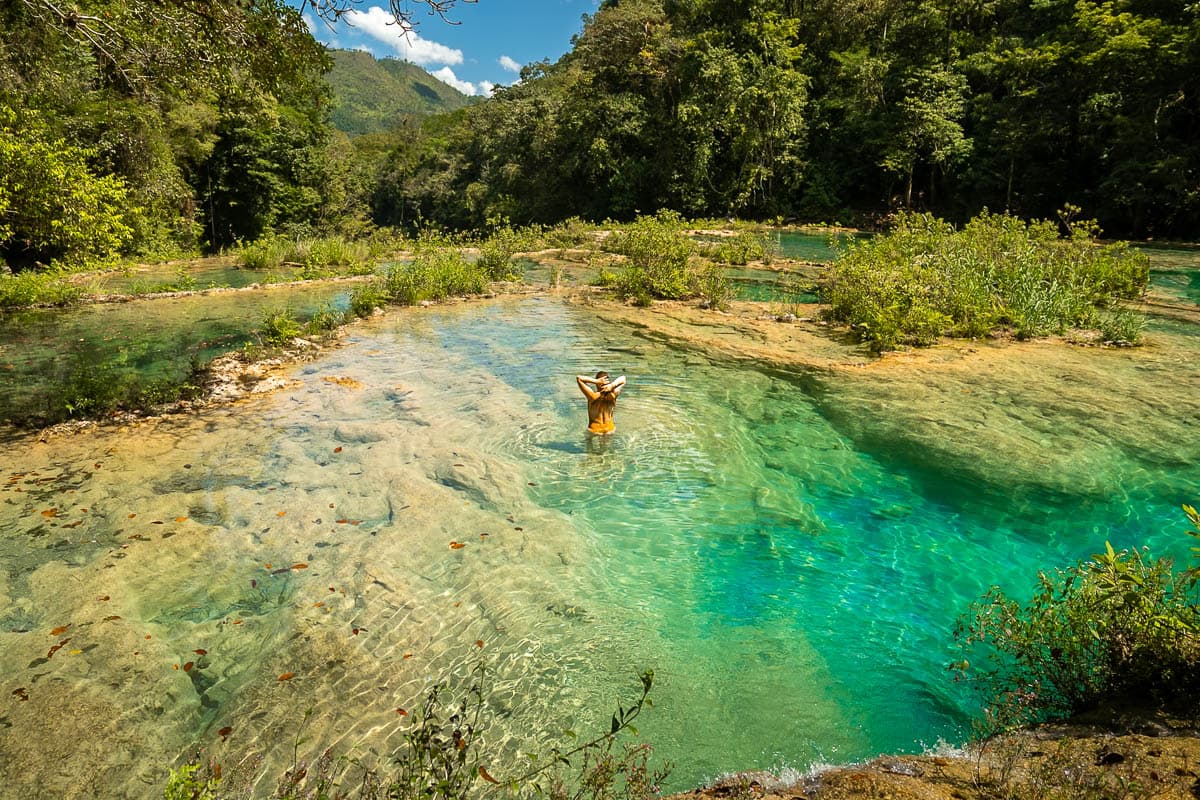 Woman squeezing her wet hair while in a pool at Semuc Champey in Guatemala 